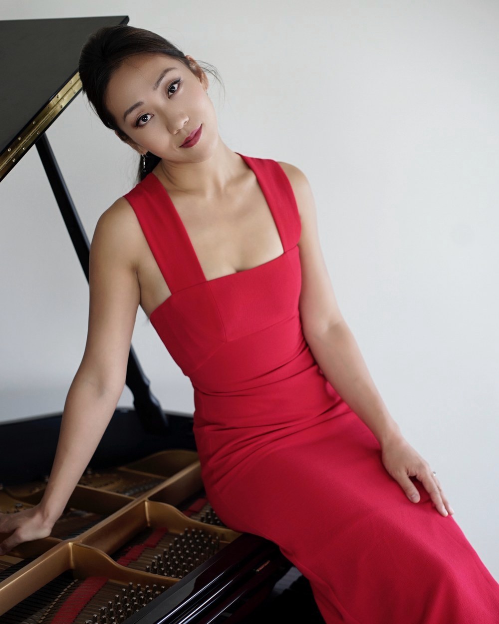 Dr. Mei Rui seated at a grand piano